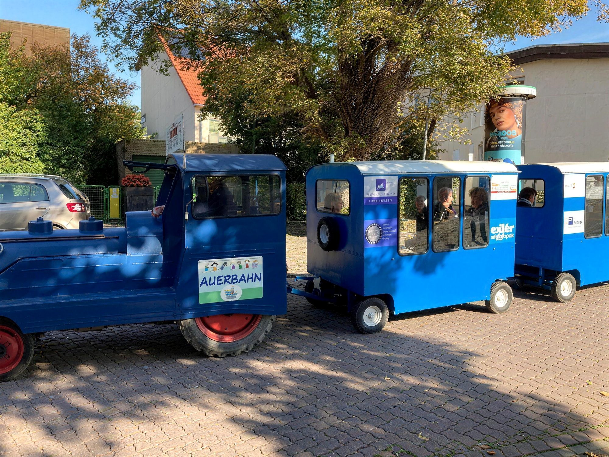 Die blaue Auerbahn mit Lok und zwei Wagen auf dem Pflaster in Auerbach